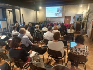 Two women presenting slides in front of an audience during a conference